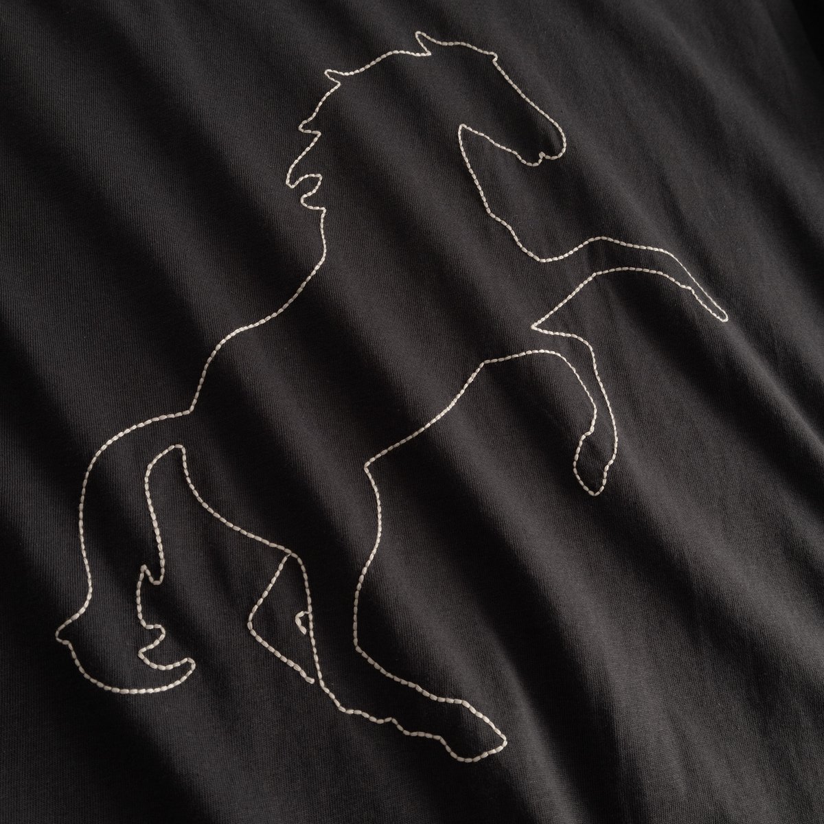 Close-up of the Wild Horse stitch embroidery on the charcoal Vadstena T-shirt.
