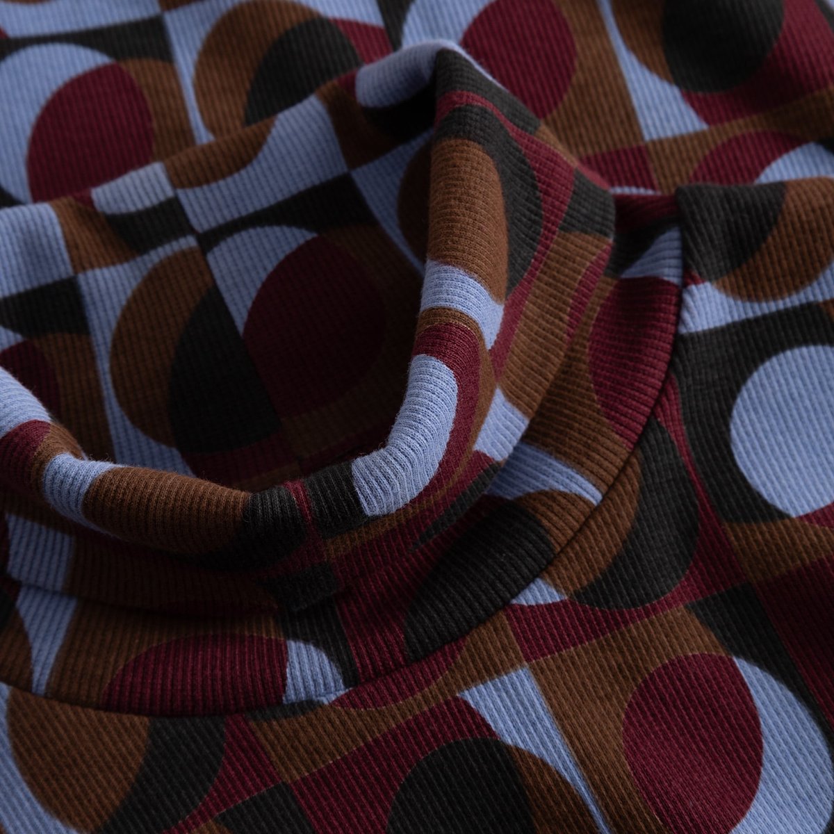 Close-up of the turtleneck collar on the Rib Top Malma, showing the ribbed texture and colorful Retro Geo print.