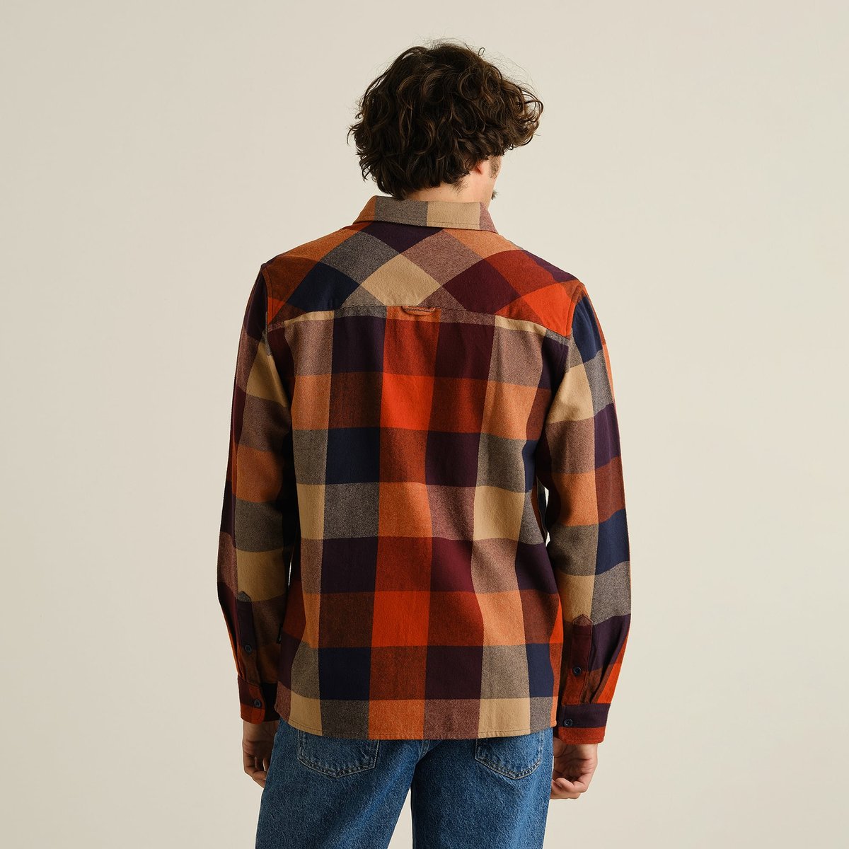 Back view of a man wearing the Rute Flannel Shirt, featuring a large, cozy plaid in warm muted colors.