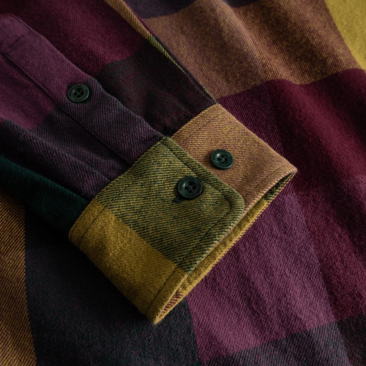 A detailed close-up of the cuff on the Shirt Rute Flannel, showcasing its bold, multi-colored check pattern and soft fabric.