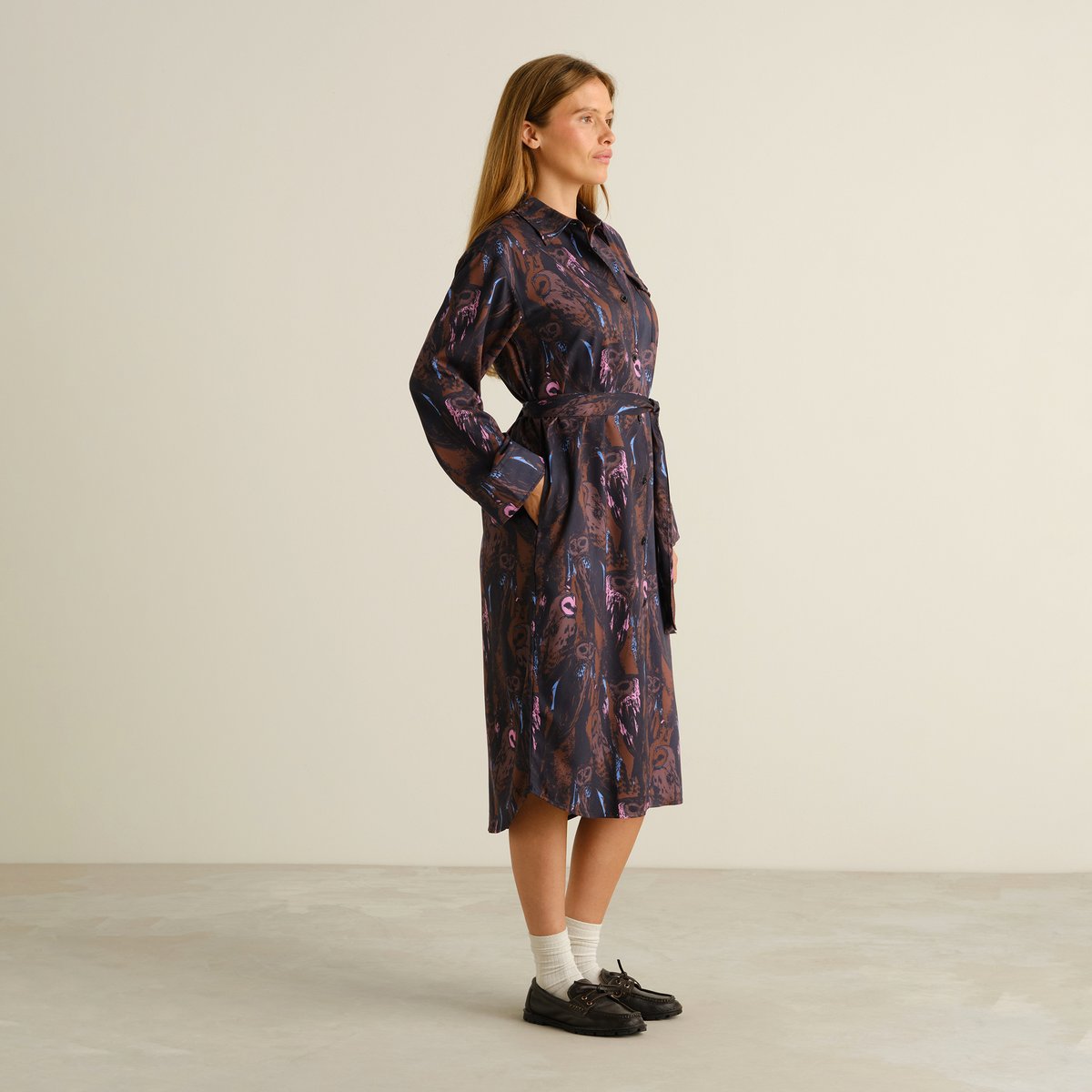 A model wears the Kvilla Shirt Dress in the Owls Multi Color print, seen from the side with her hands in the pockets.