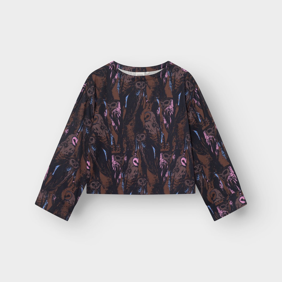 A flat-lay photo of the Top Udda, showing its boxy fit, wide sleeves, and expressive multi-color owl print.