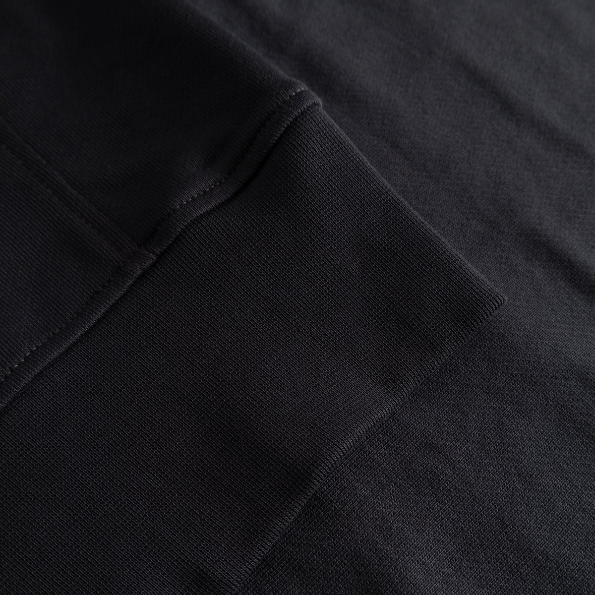 A close-up of the soft, ribbed cuff on the heavyweight organic cotton Bettna Sweatshirt in Phantom Black.
