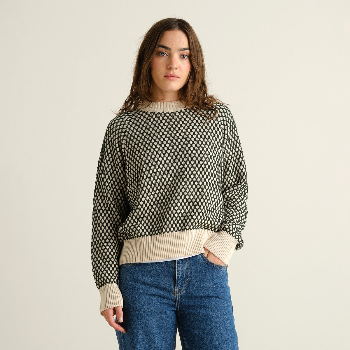 Modell som bär den grön- och vitmönstrade stickade tröjan Husie Bubble Knit med ett par klassiska blåjeans.