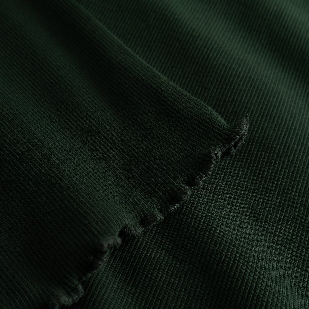 Close-up of the Rib Dress Lofta in Dark Green, highlighting the soft ribbed fabric and the delicate lettuce edge detail.