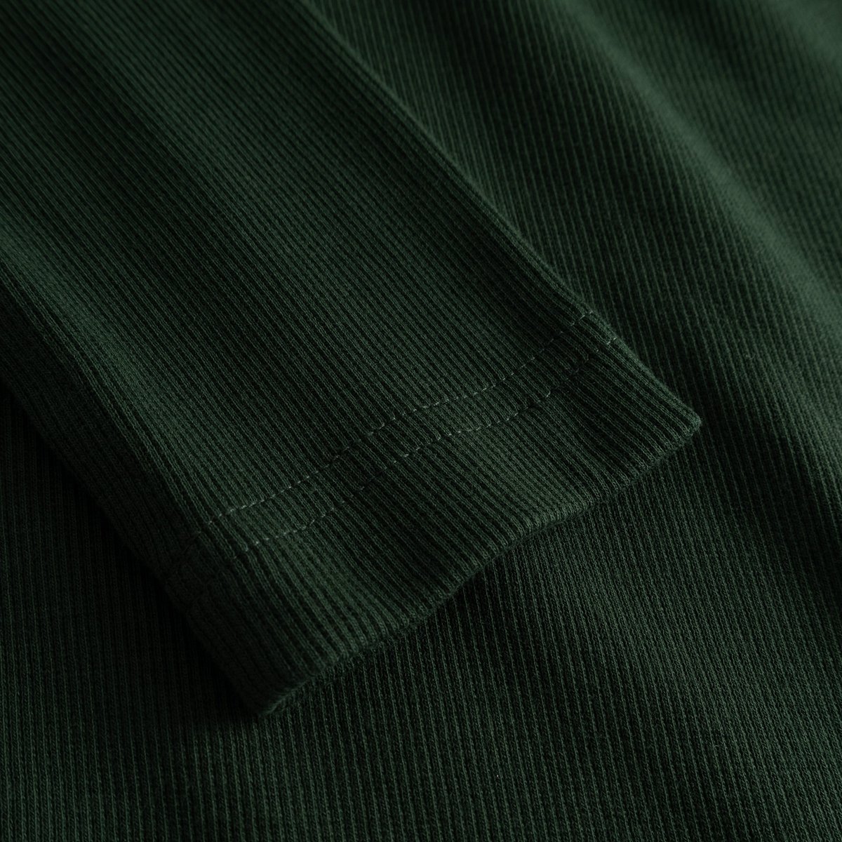 A detailed close-up of the sleeve on the Rib Top Malma, showcasing the fine ribbed texture in a deep dark green.