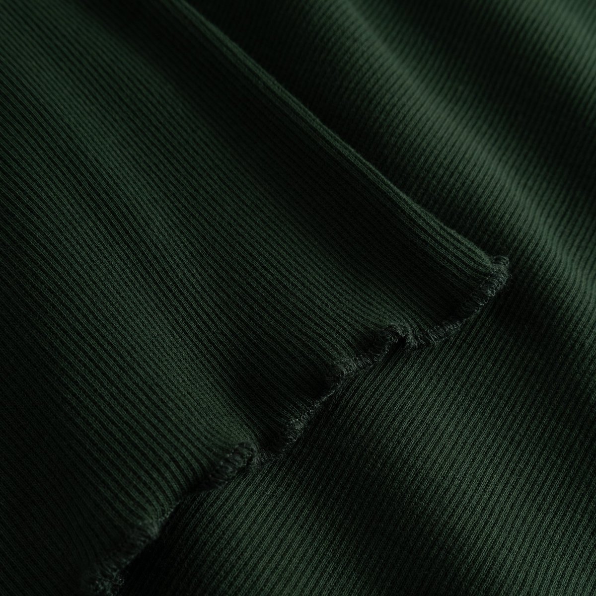 A close-up of the Rib Top Ryd in Dark Green, showing the soft ribbed texture and delicate wavy finish of the lettuce seam.