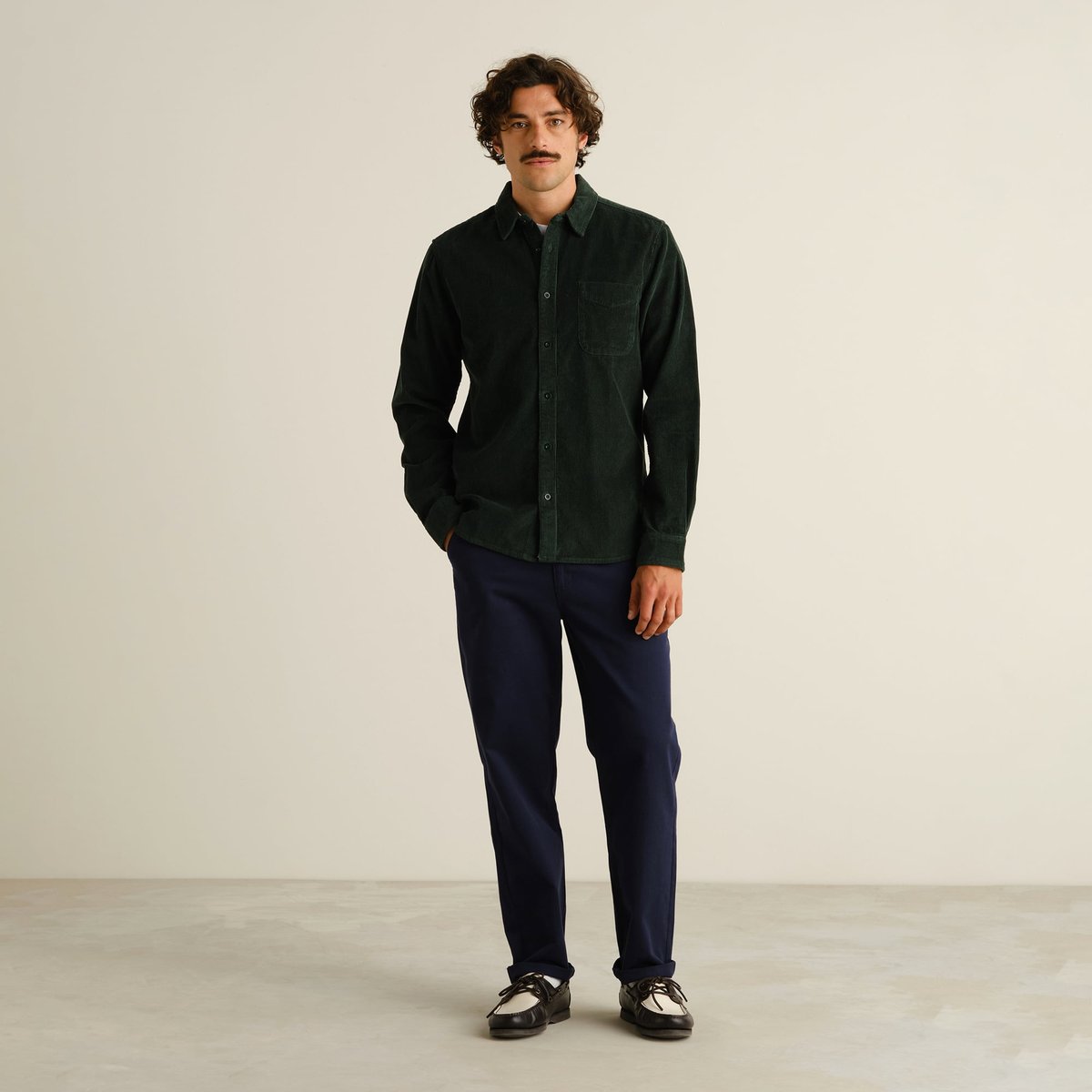 A model looks sharp in the dark green Varberg Corduroy Shirt, paired with navy trousers for a classic, cool style.