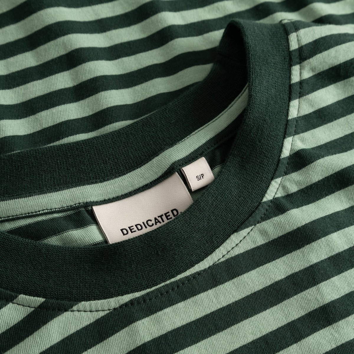 Close-up of the brand label and dark green collar on the striped T-shirt Vadstena in Dark Green/Granite Green.