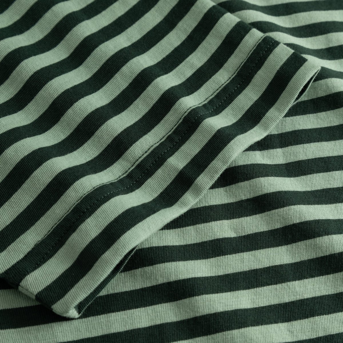 Close-up shot of the striped fabric and sleeve detail on the T-shirt Vadstena in dark and granite green.
