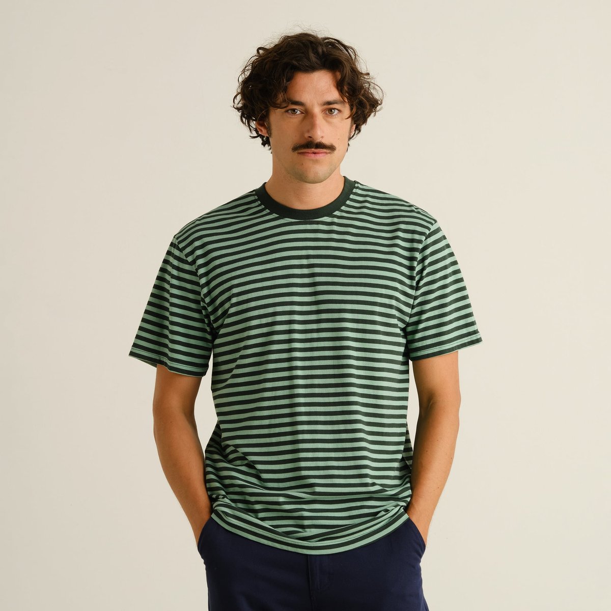 Front view of a male model wearing the striped Stockholm t-shirt in dark green and granite green.