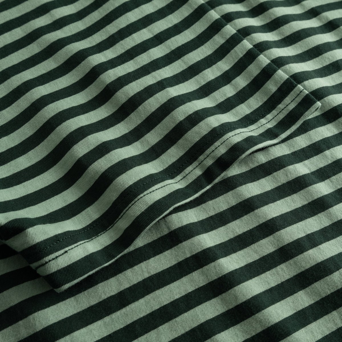 Detailed shot of the organic cotton fabric of the Stockholm T-shirt in a dark green and granite green striped pattern.