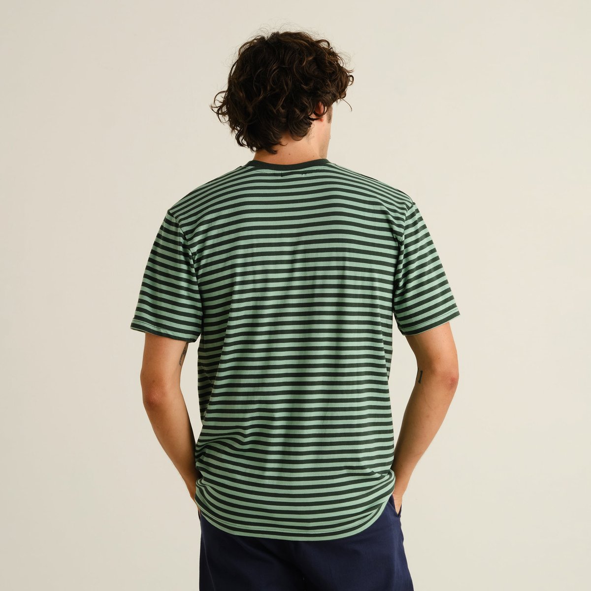 Man seen from behind wearing the T-shirt Stockholm Stripes in Dark Green and Granite Green.