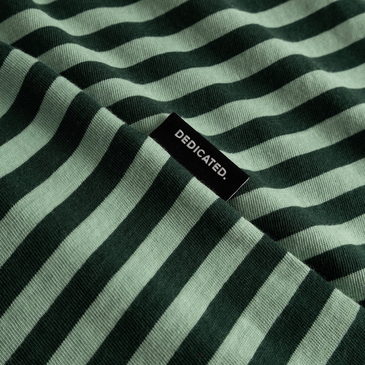 Close-up of the T-shirt Stockholm Stripes in dark and granite green, showing the fabric texture and black Dedicated label.