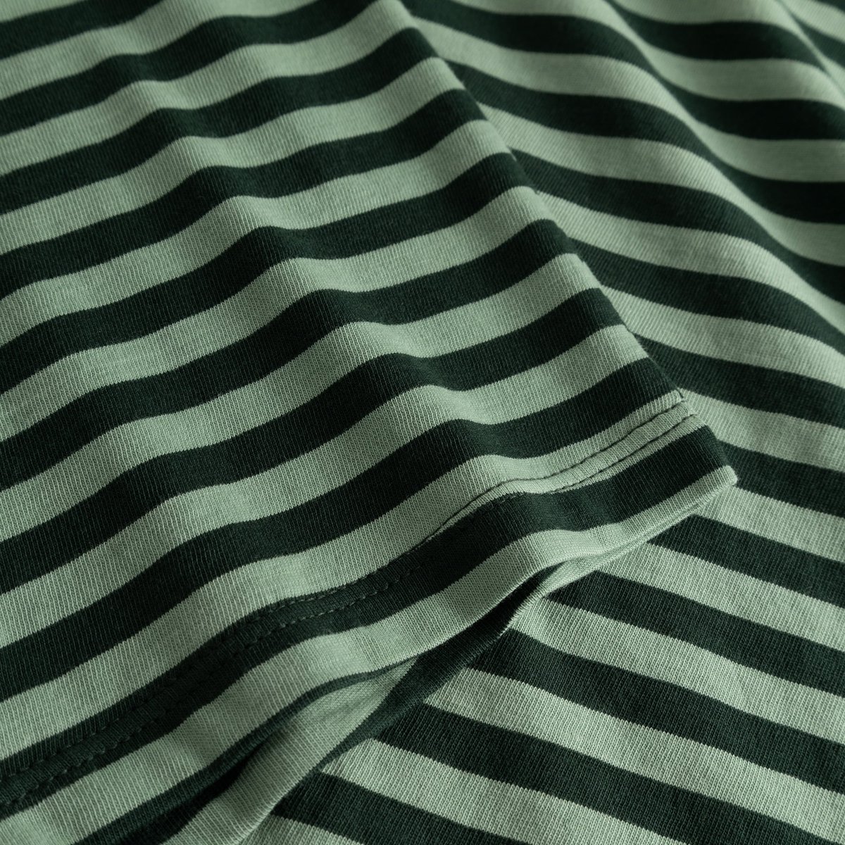 Close-up of the Top Humledal's soft jersey fabric, featuring dark green and granite green stripes and sleeve hem detail.