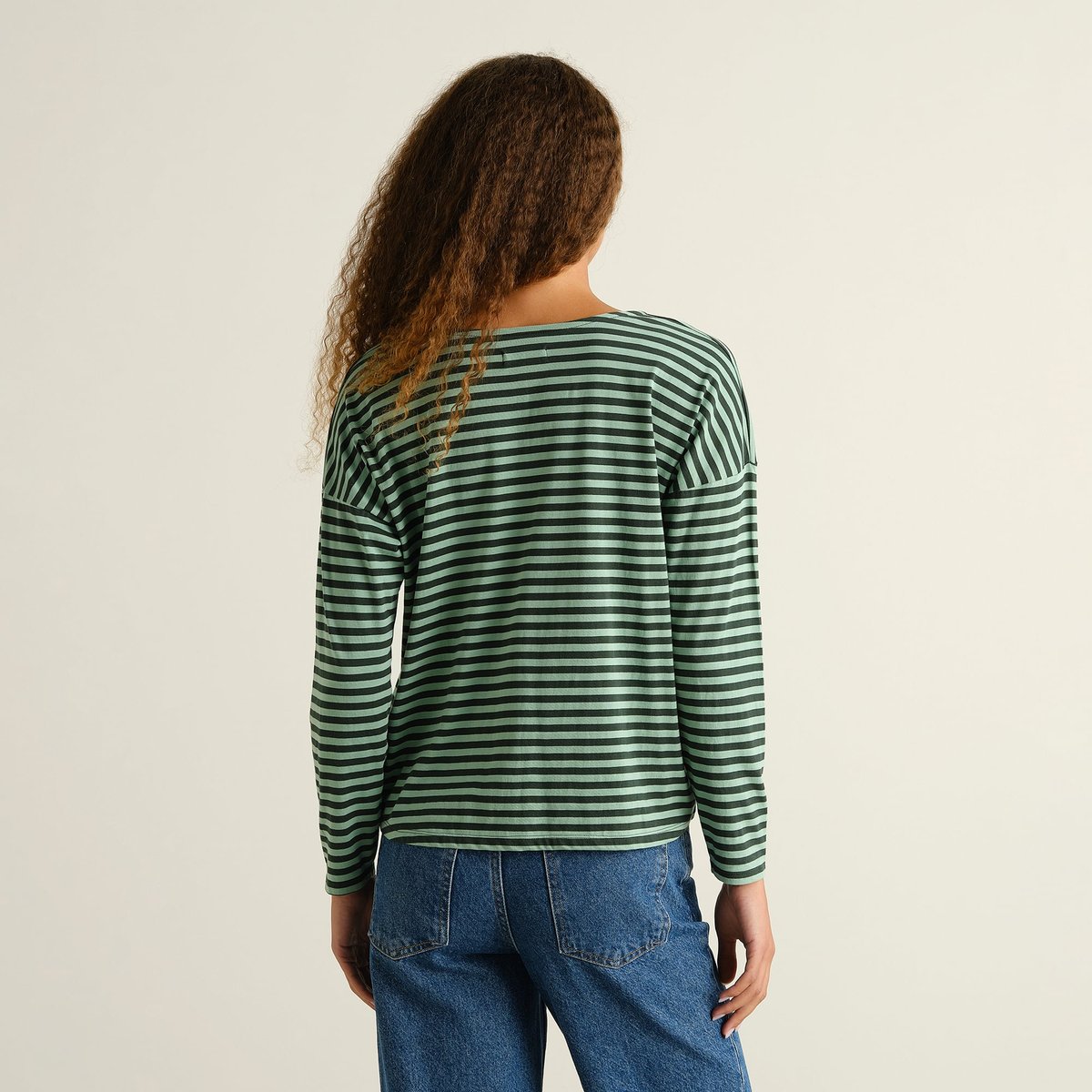 Model seen from behind wearing the striped Top Humledal in Dark Green/Granite Green, showing its relaxed, boxy fit.