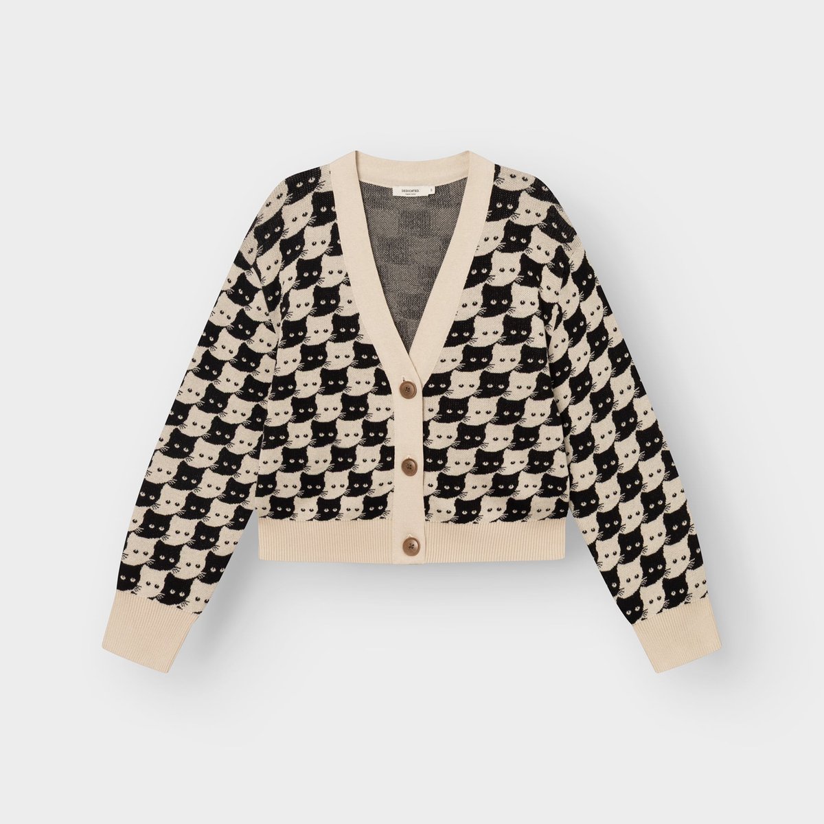 Studio shot of the Kanan cardigan in Oat White. This knitted V-neck is covered in a playful pattern of black and white cats.