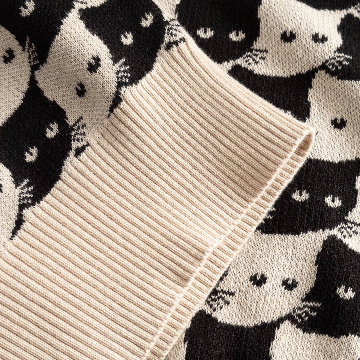 Detailed shot of the oat white ribbed cuff and jacquard cat pattern on the organic cotton Kanan Cardigan.