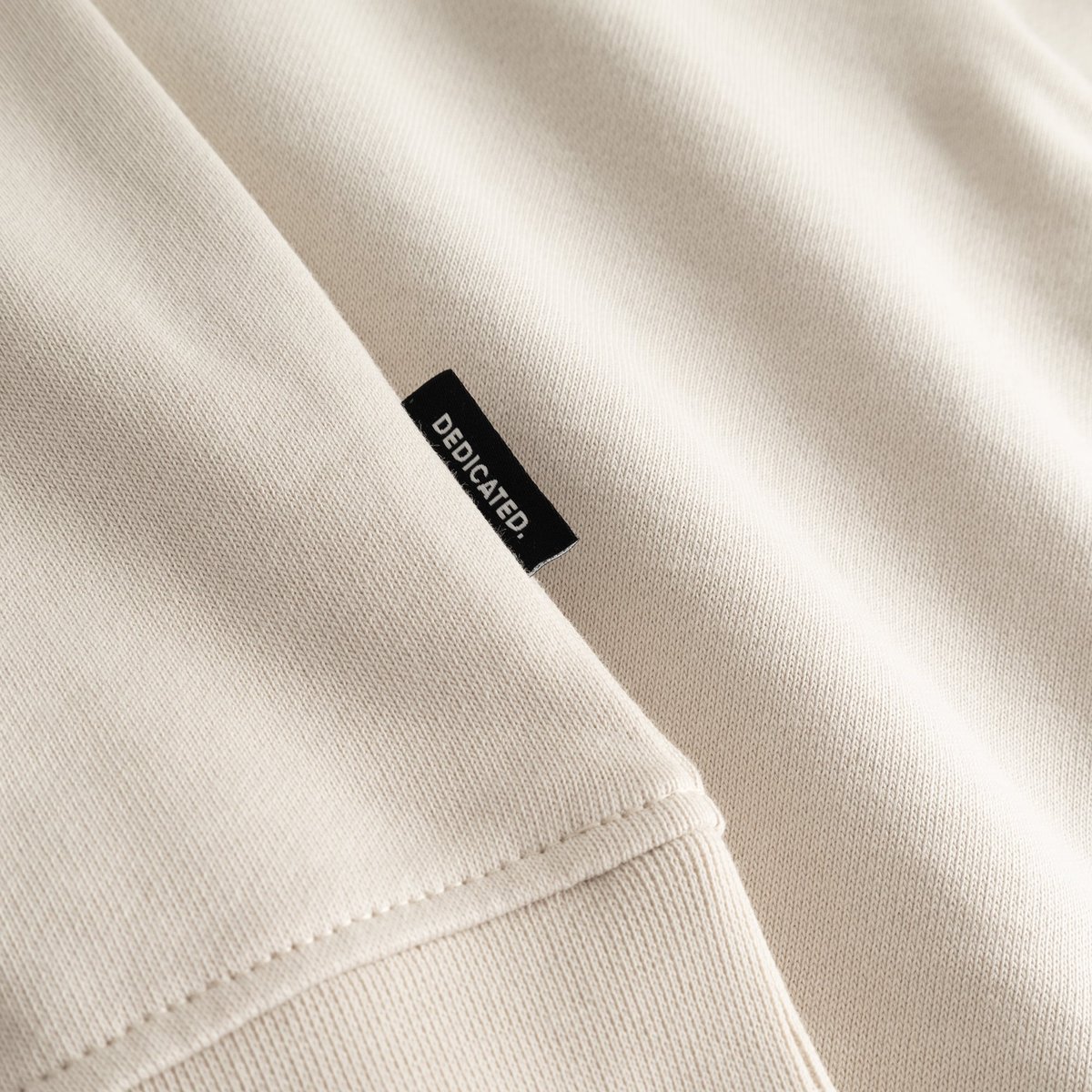 A close-up of the Sweatshirt Ystad in Oat White, highlighting the soft fabric and the signature Dedicated side label.