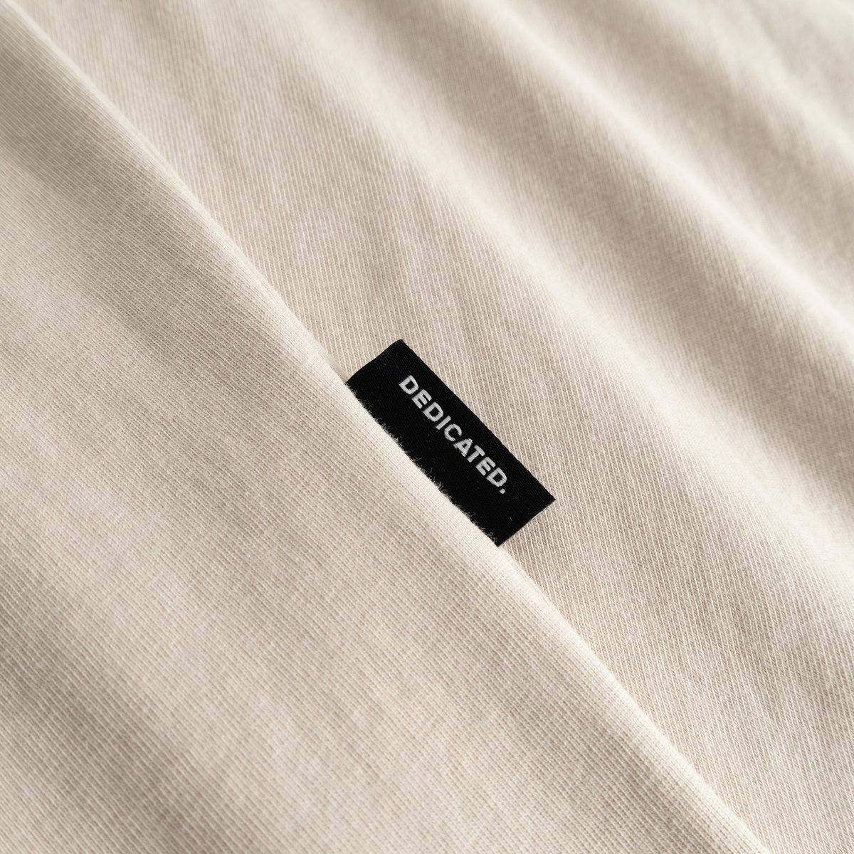 A close-up look at our T-shirt Stockholm in Oat White, featuring the subtle and classic Dedicated side label.