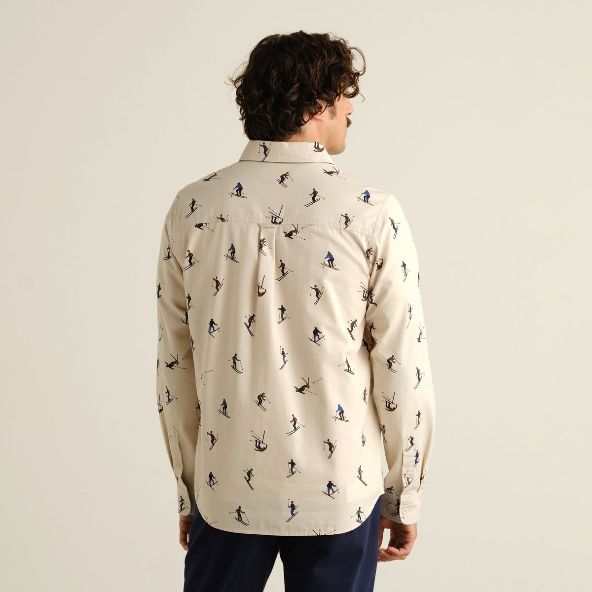Back view of a model wearing the Shirt Lunnevik Ski Team Oat White, showing the playful all-over skier print.