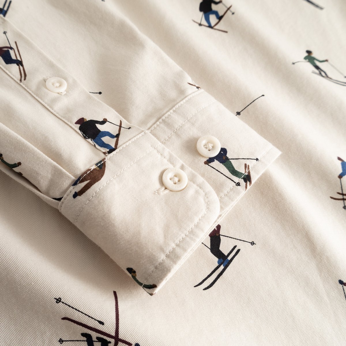 A close-up detail of the cuff on the oat white Shirt Lunnevik, showcasing the fun all-over ski team print.