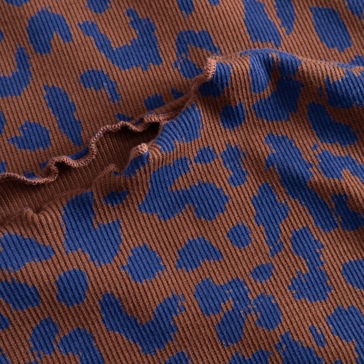 A close-up of the Rib Dress Lofta's fabric, featuring a blue and brown leopard print on a ribbed texture with a wavy seam.