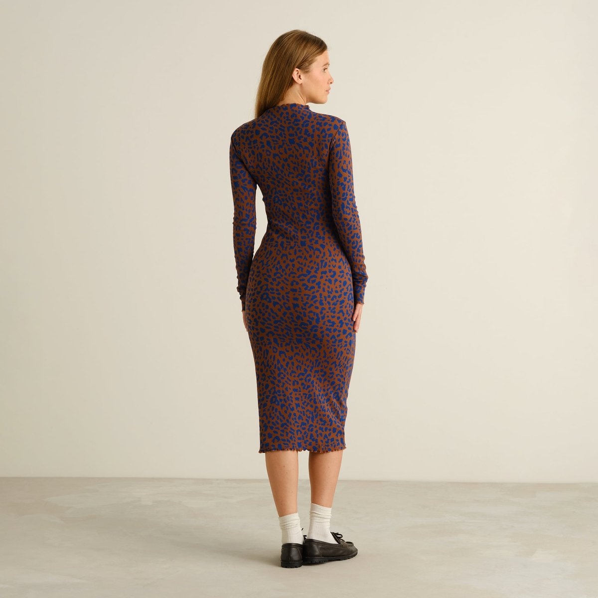 Back view of a woman wearing the Lofta Rib Dress in Leopard Light Brown, styled with white socks and black loafers.