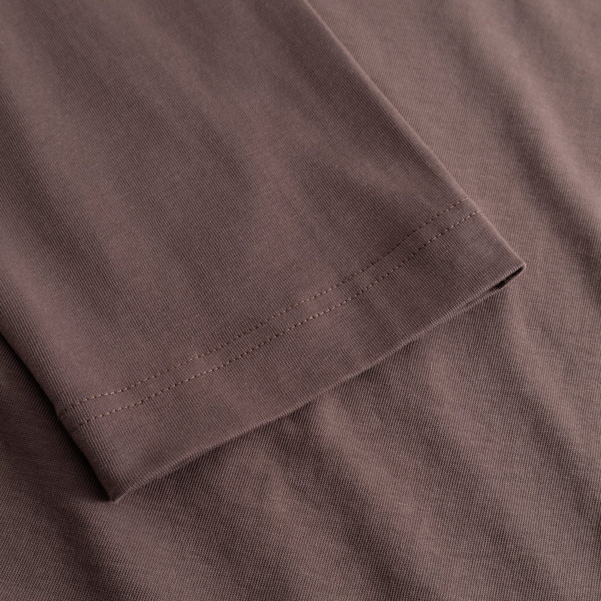 A detailed close-up of the sleeve on the Vreta long-sleeve T-shirt, showing the fine stitching and soft Sparrow Brown fabric.