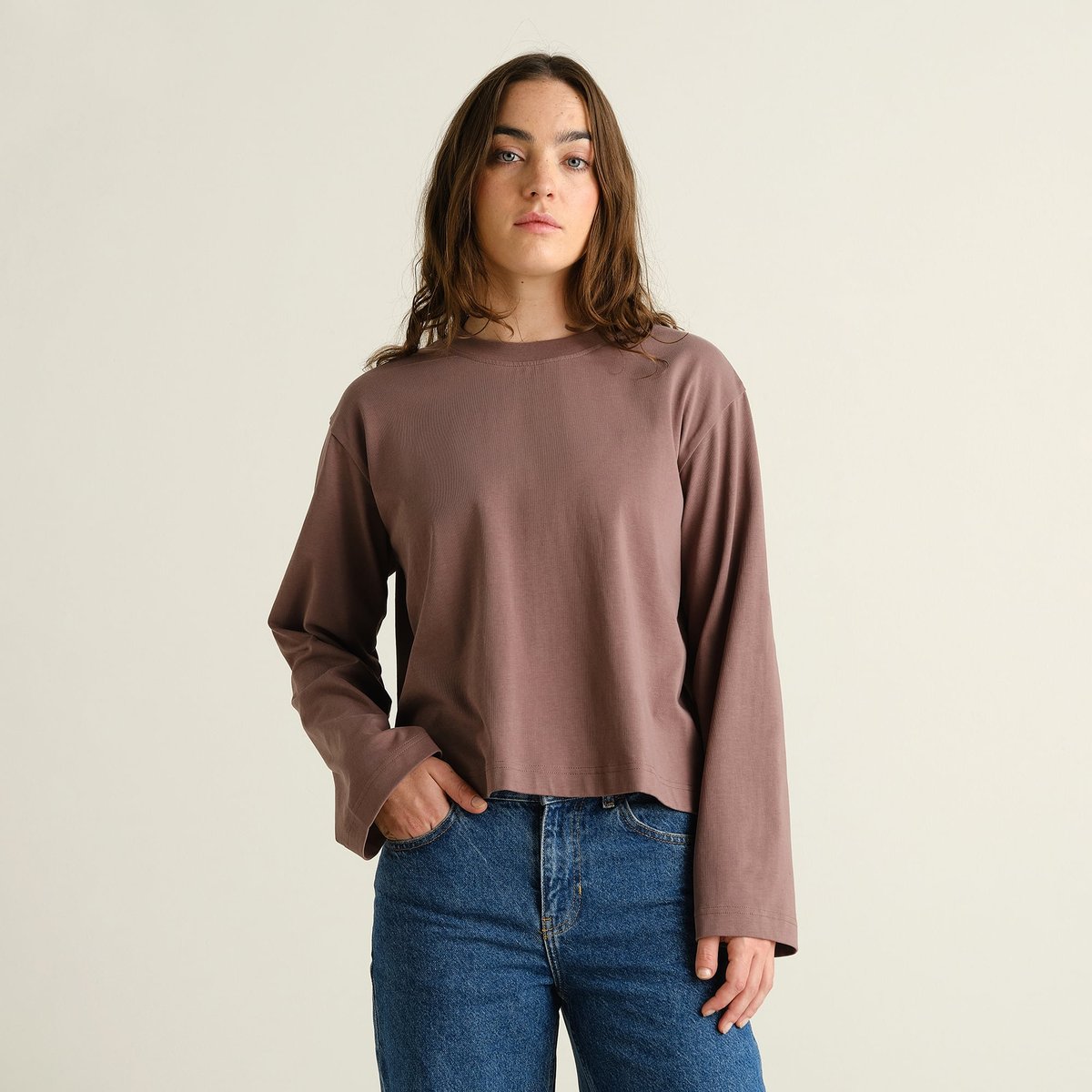 Model wearing the long-sleeved Vreta T-shirt in Sparrow Brown, showing its relaxed, boxy fit with wide sleeves.