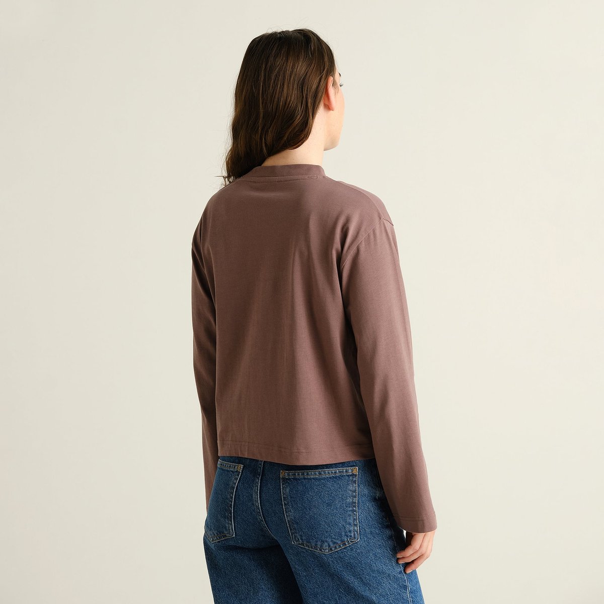 Model seen from the back, wearing the brown Vreta long-sleeved t-shirt with a pair of classic blue jeans.