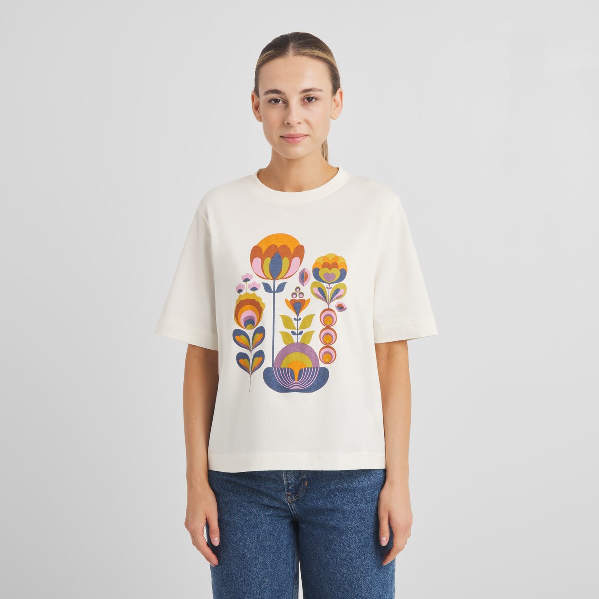 Model seen from the front wearing the T-shirt Vadstena Autumn Harvest in off-white, styled with blue jeans.