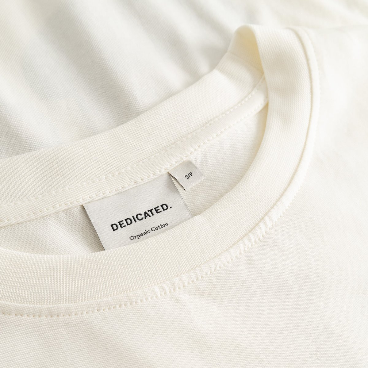 Close-up detail shot of the ribbed crew neck collar and brand label inside the off-white T-shirt Vadstena Autumn Harvest.