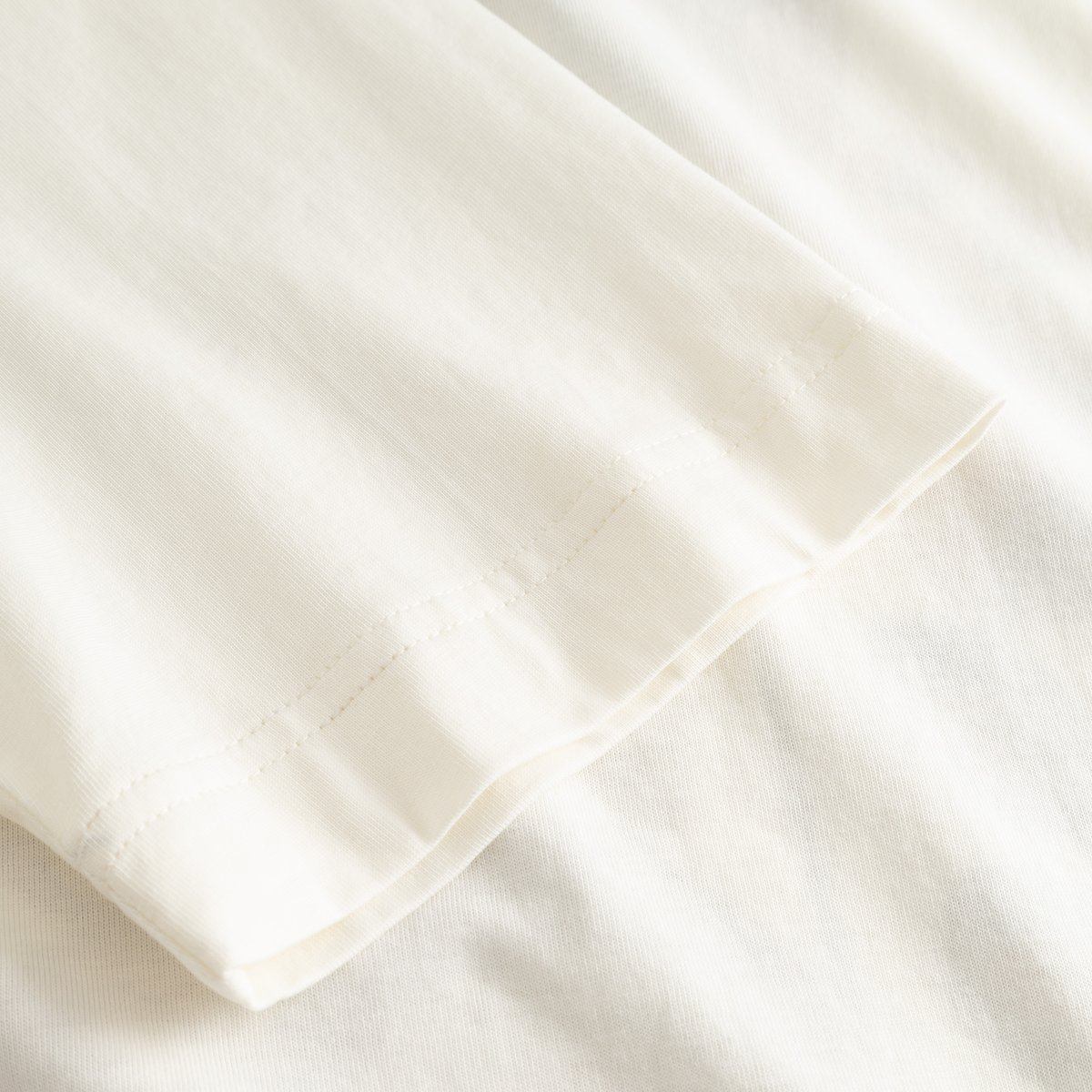 Detailed shot of the sleeve hem on the off-white T-shirt Vadstena Autumn Harvest, showing the soft organic cotton fabric.