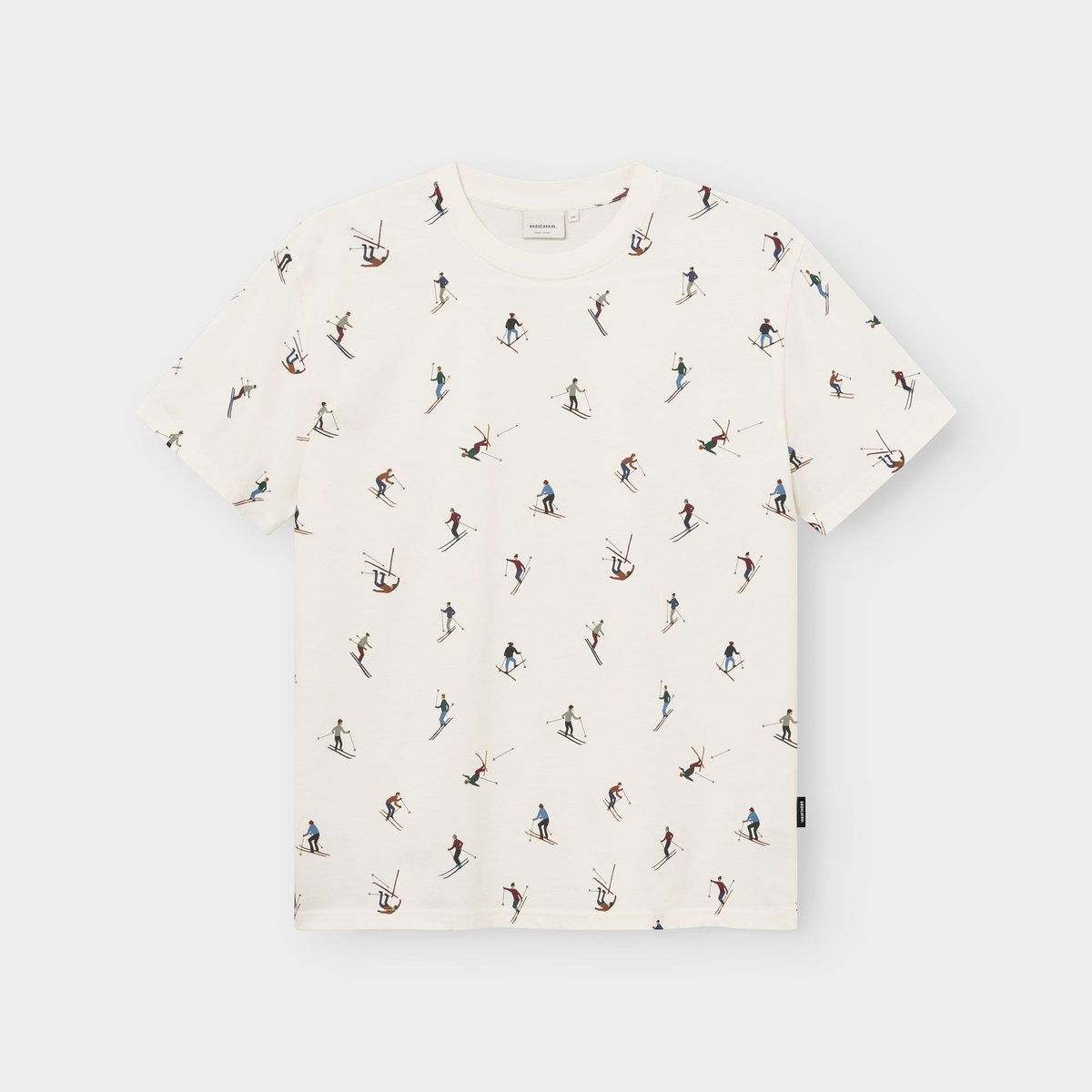 Flat lay of an off-white t-shirt with a fun all-over print featuring colorful illustrations of skiers.