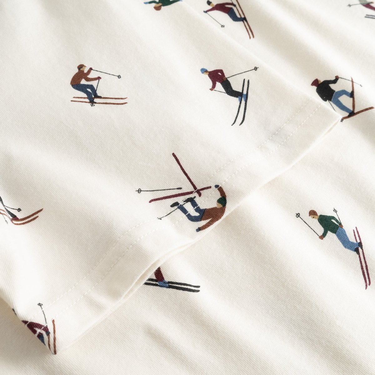 Close-up detail of the off-white Stockholm Ski Team t-shirt, showing the all-over print of colorful skiers on the sleeve.