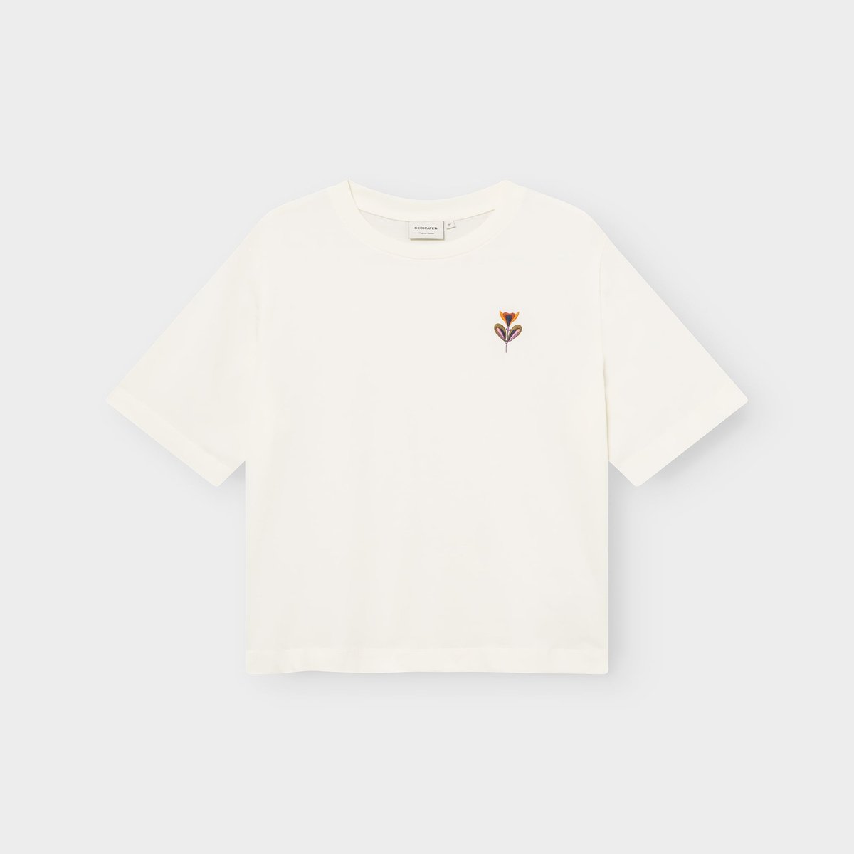 Flat lay of the off-white Vadstena t-shirt, featuring a small embroidered 'Autumn Harvest' flower on the chest.