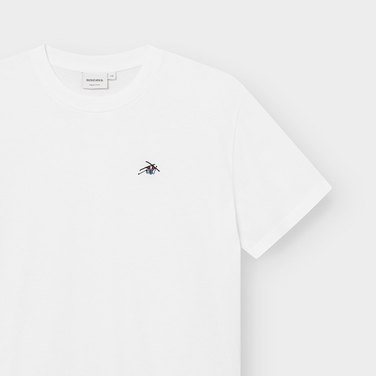 Close-up of the white T-shirt Stockholm Ski Crash, showing the playful skier embroidery on the chest and the brand label.
