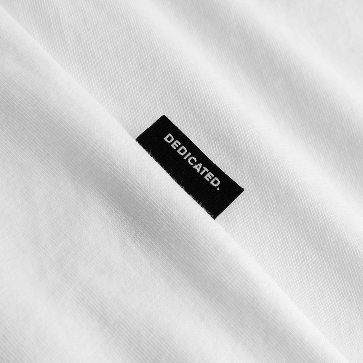 Close-up detail of the T-shirt Stockholm Fondue in white, highlighting the soft fabric and signature Dedicated label.
