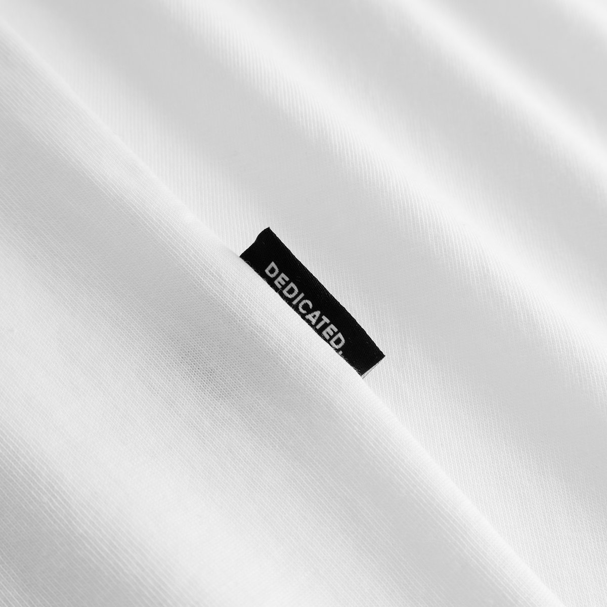 The perfect detail: a close-up shot of the Dedicated label on the white T-shirt Stockholm Friday Celebration.