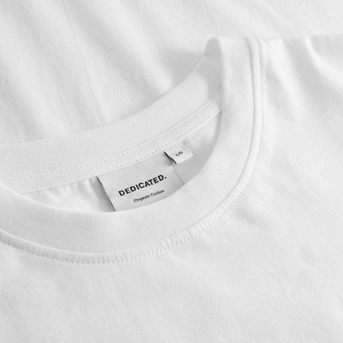 Close-up of the crisp white organic cotton and ribbed collar on the Stockholm T-shirt, with the Dedicated brand label.