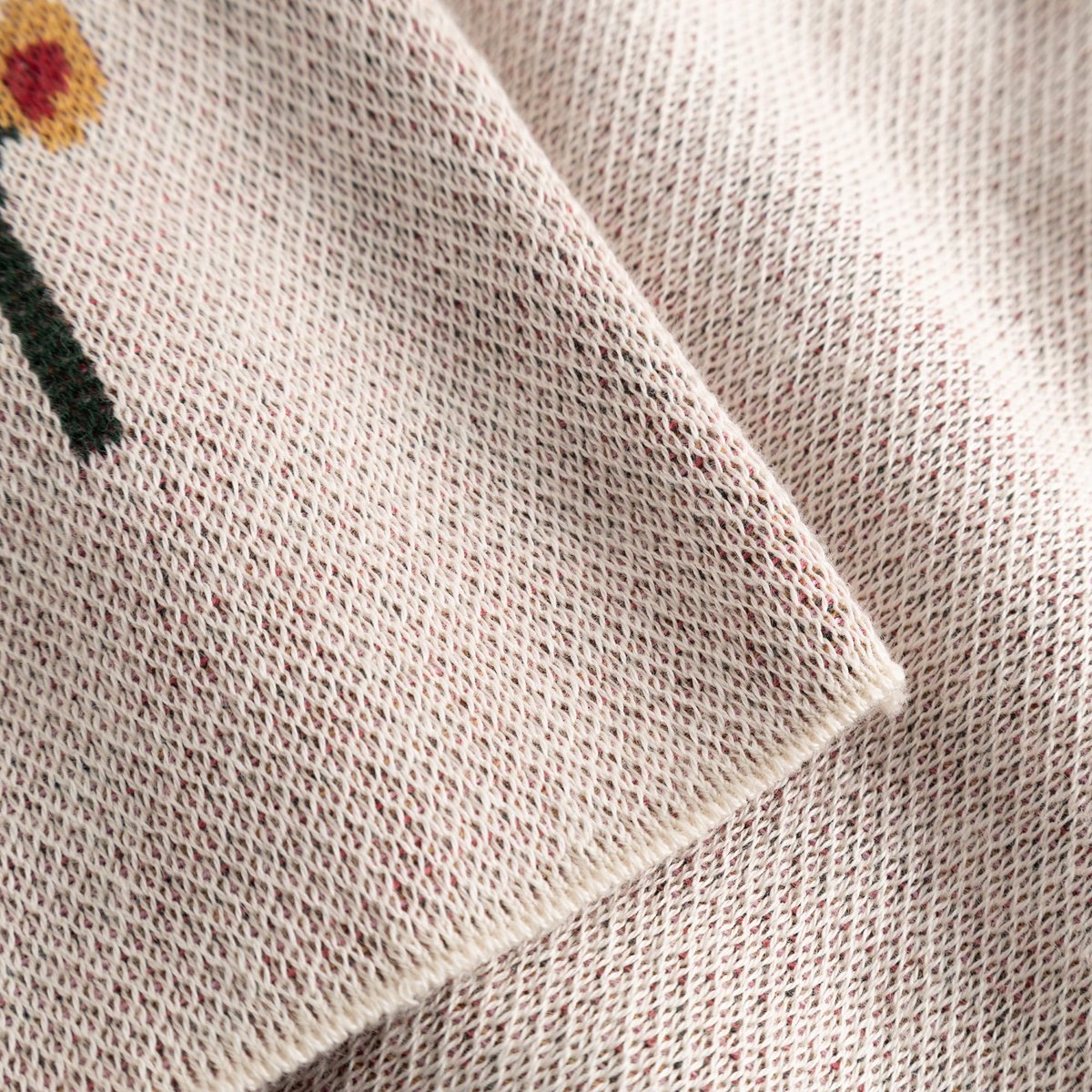 Close-up of the organic cotton jacquard knit on the Sweater Limhamn, showing the texture and Folk Flower detail.