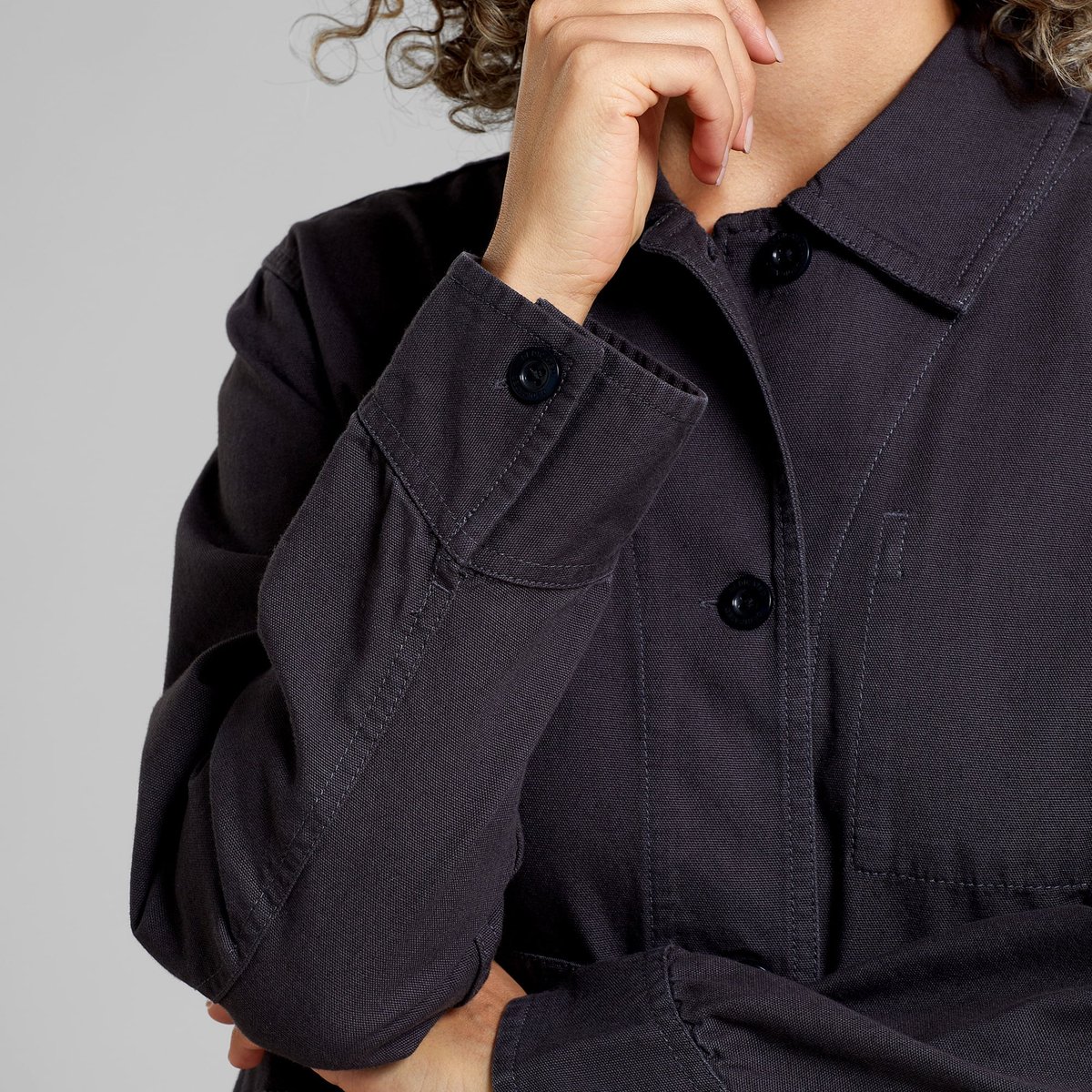 A model wears the relaxed-fit Stiby shirt jacket in Phantom Black, showing a close-up of the buttoned cuff and collar.
