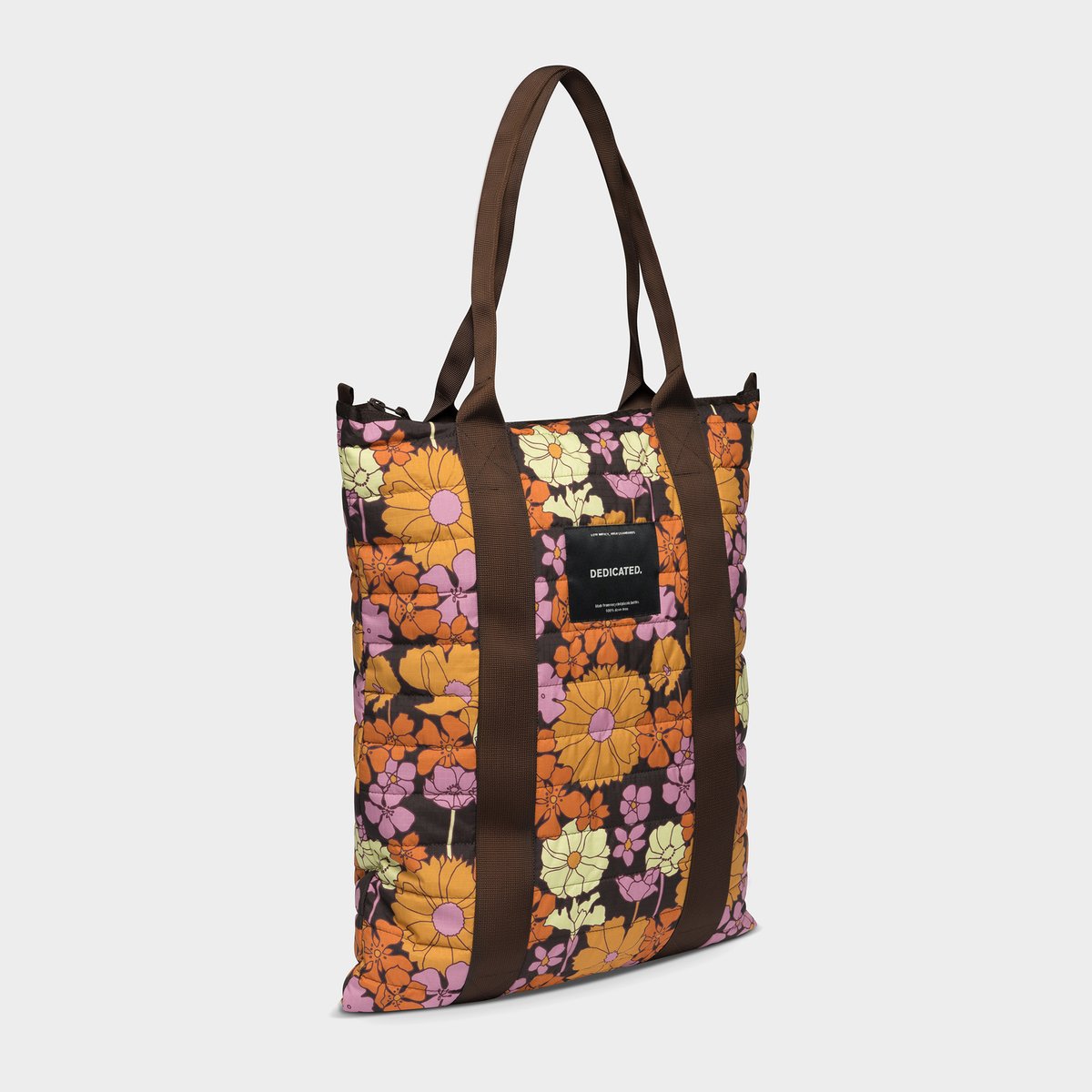 Studioaufnahme der gesteppten Tragetasche Kastrup mit auffälligem Flower-Power-Print mit Blumen in Orange, Pink und Gelb.