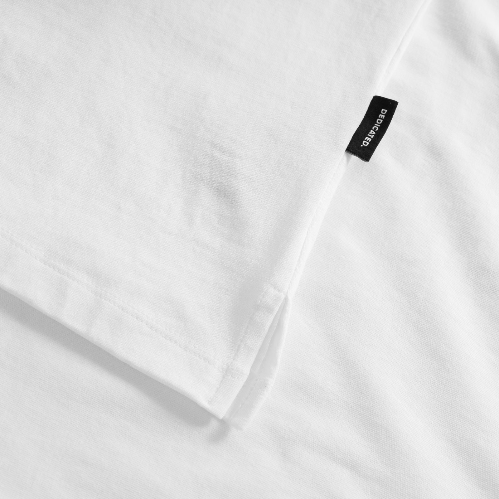 A close-up look at the neat side slit and black Dedicated brand tag on our white T-shirt Visby Pizza Love.