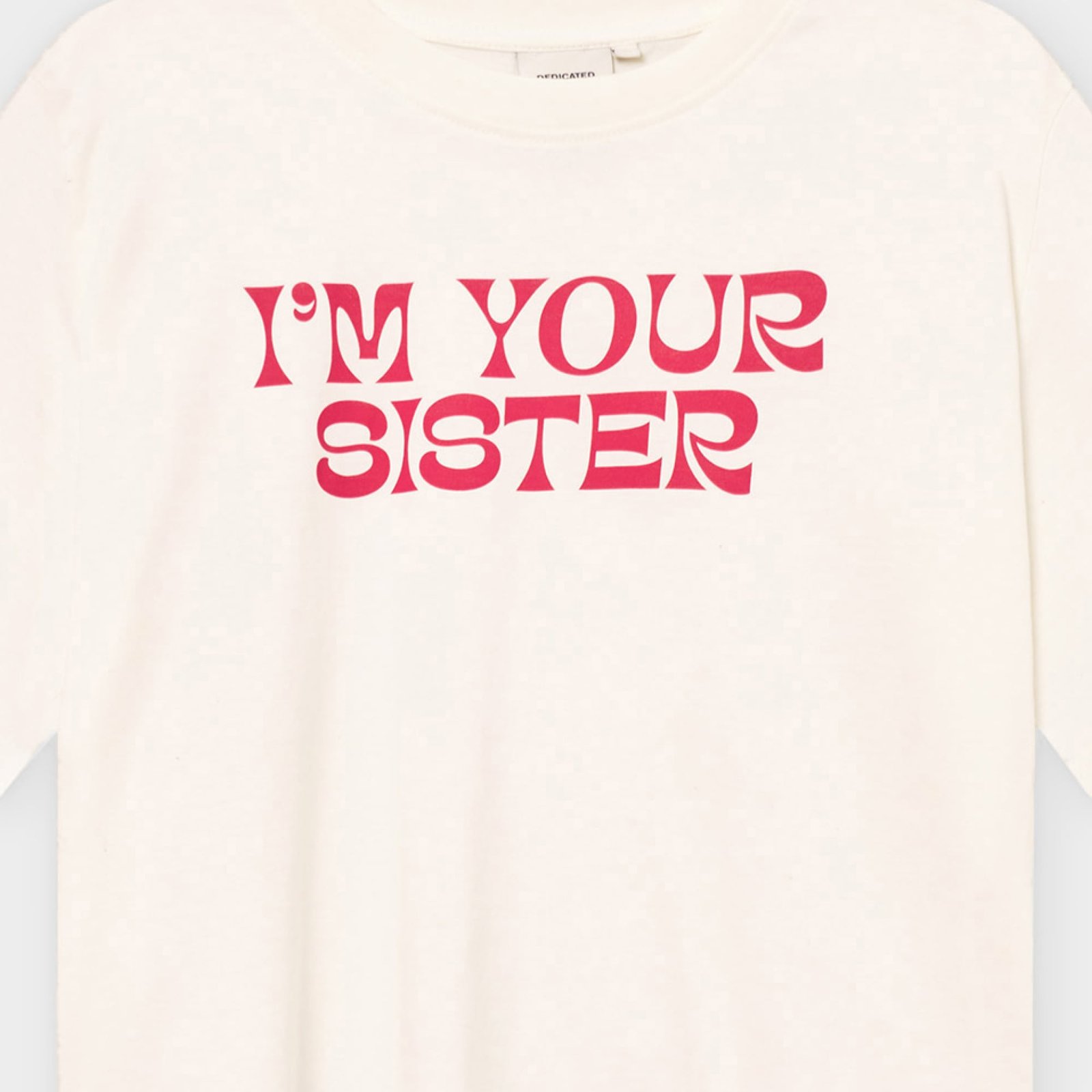 Close-up of the off-white T-shirt Vadstena Sister, showing the bold 'I'M YOUR SISTER' print in a pink-red retro font.