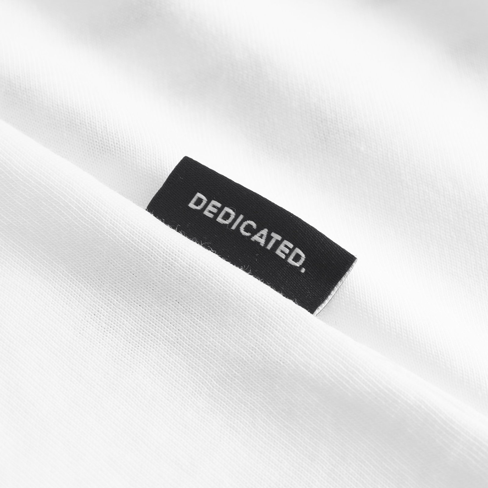 Close-up of the signature black Dedicated label, a mark of quality on the off-white Stockholm Beach Habitat t-shirt.