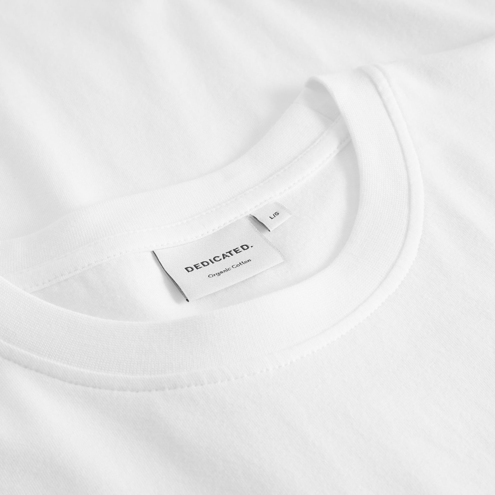 Nahaufnahme des Kragens und Markenetiketts des weißen T-Shirts Stockholm Pour Some White aus Bio-Baumwolle.