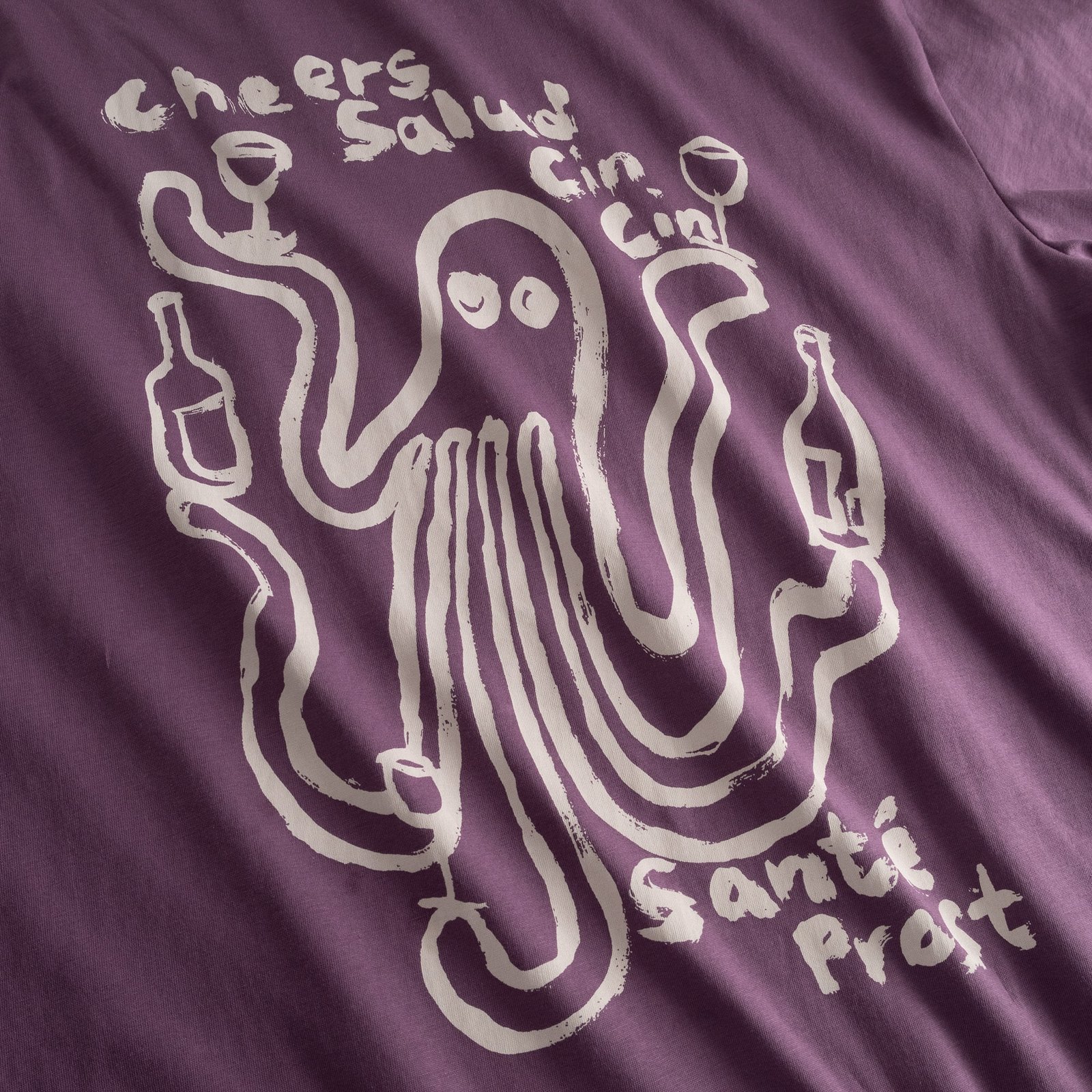 Nahaufnahme des verspielten Oktopus-Prints auf dem lila T-Shirt Stockholm Cheers Salud.