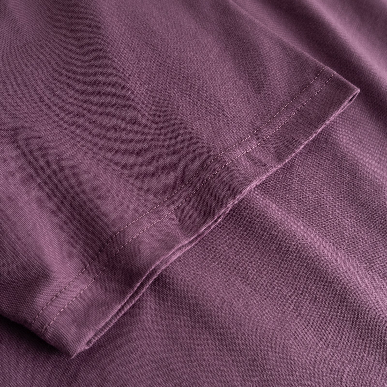 Närbild på ärmen på T-shirt Stockholm Base Berry Purple, som visar tygets struktur och sömmar.